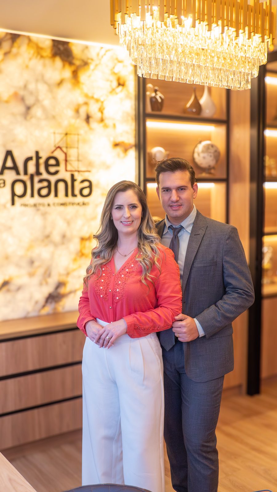 A dupla da Arte na Planta no escritório, diante da parede com a marca